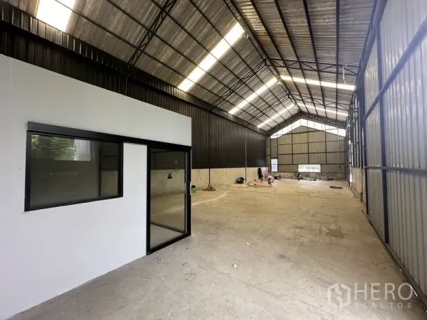 Warehouse for rent in Lat Phrao, Bangkok - Spacious warehouse interior with high gable roof, skylights, concrete floor and a glass-partition office.
