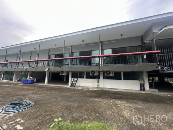 Standalone for rent in Prawet, Bangkok - Rear exterior of raised two-storey building with balcony and open parking area.