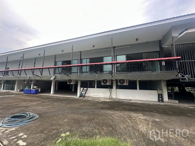 Standalone for rent in Prawet, Bangkok - Rear exterior of raised two-storey building with balcony and open parking area.
