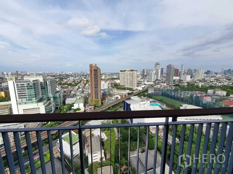 Condominium for sale in Khlong Toei, Bangkok - High-floor balcony view of the Bangkok skyline with BTS tracks and city towers.