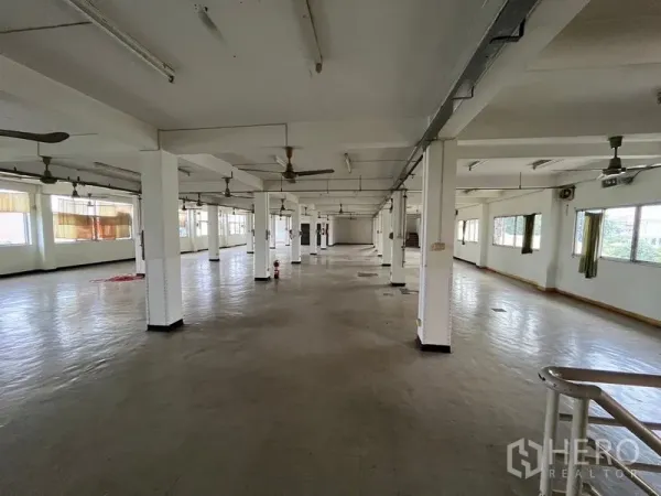 Shophouse for rent in Khlong Toei, Bangkok - Expansive open-plan upper floor with rows of columns, ceiling fans and windows providing natural light.