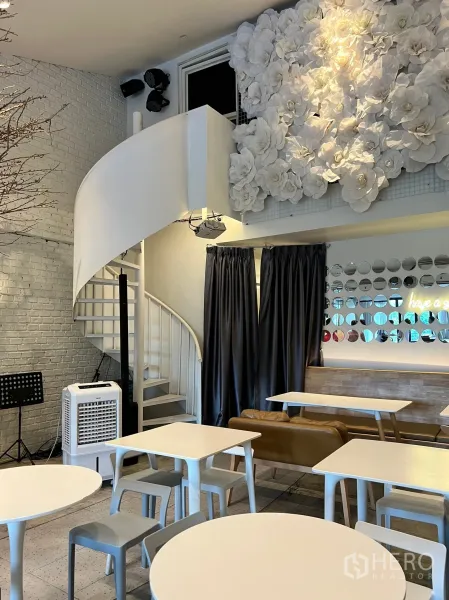 Retail Space for rent in Watthana, Bangkok - Bright retail cafe interior with a white spiral staircase, textured brick walls, floral feature wall and modern tables.