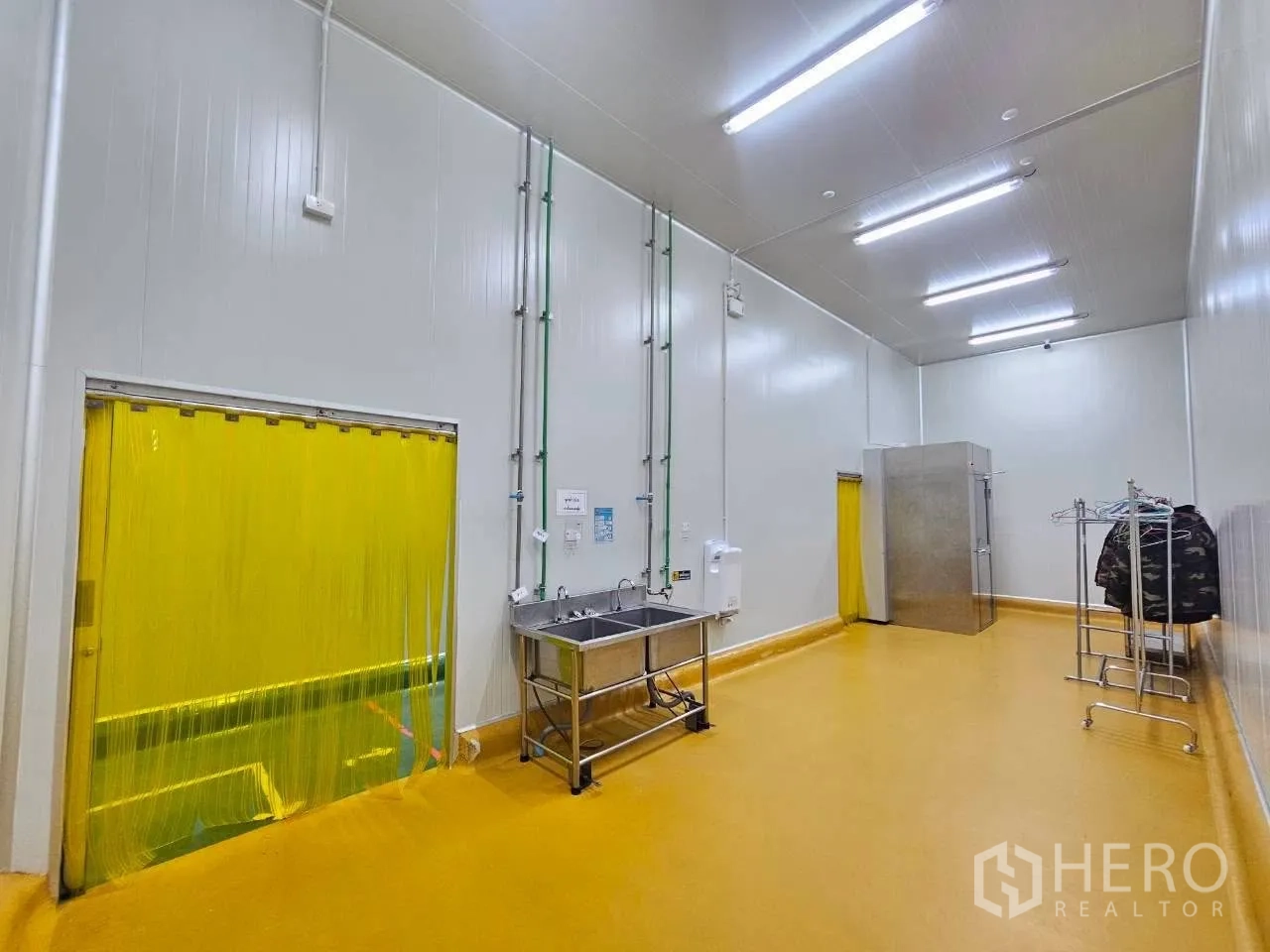Factory for rent in Mueang Samut Sakhon, Samut Sakhon - Sanitary room with stainless sink, yellow strip door, and garment rack.