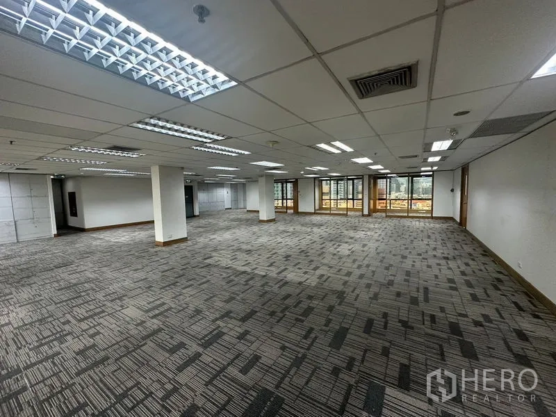 Office Space for rent in Khlong Toei, Bangkok - Open workspace with columns, drop-ceiling lights, and city-facing windows.