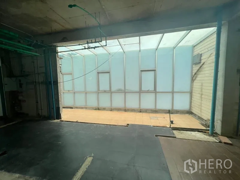 Retail Space for rent in Watthana, Bangkok - Open-plan unit with translucent roof panels, exposed piping, and a side patio.