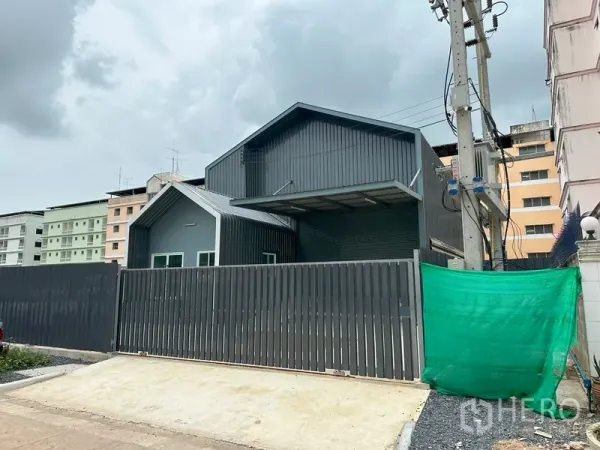 工厂 出租在Khlong Luang, Pathum Thani - 灰色金属外墙的现代工厂外观，带高围栏与城市背景。