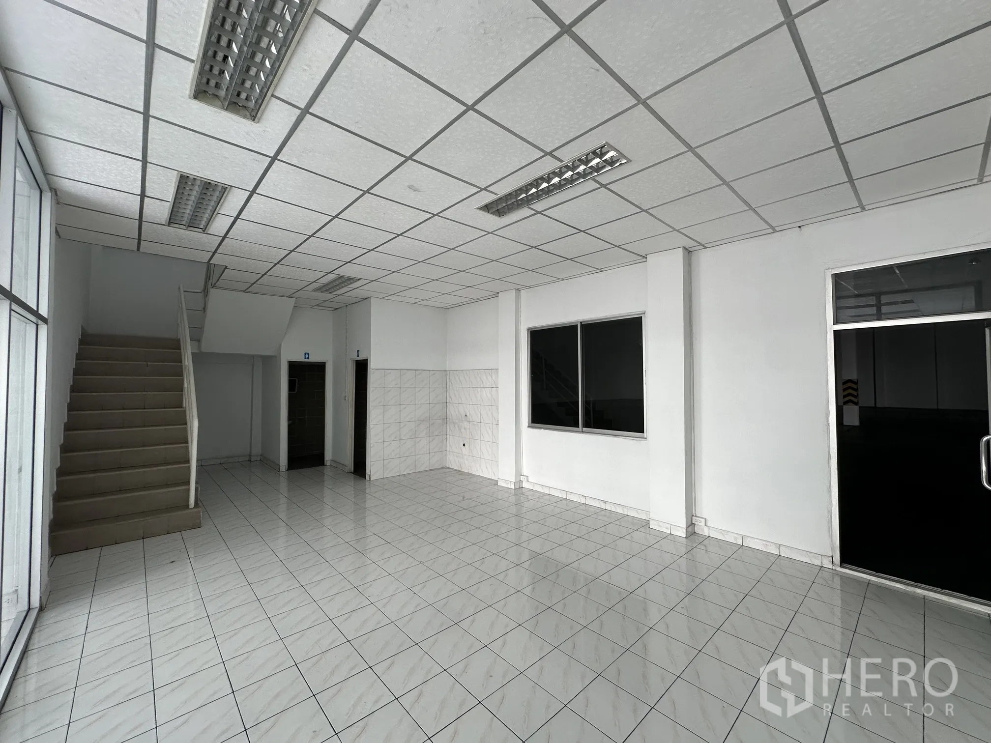 Warehouse for rent in Wang Noi, Phra Nakhon Si Ayutthaya - Ground-floor office area with tiled flooring, staircase and glass entry beside the warehouse.