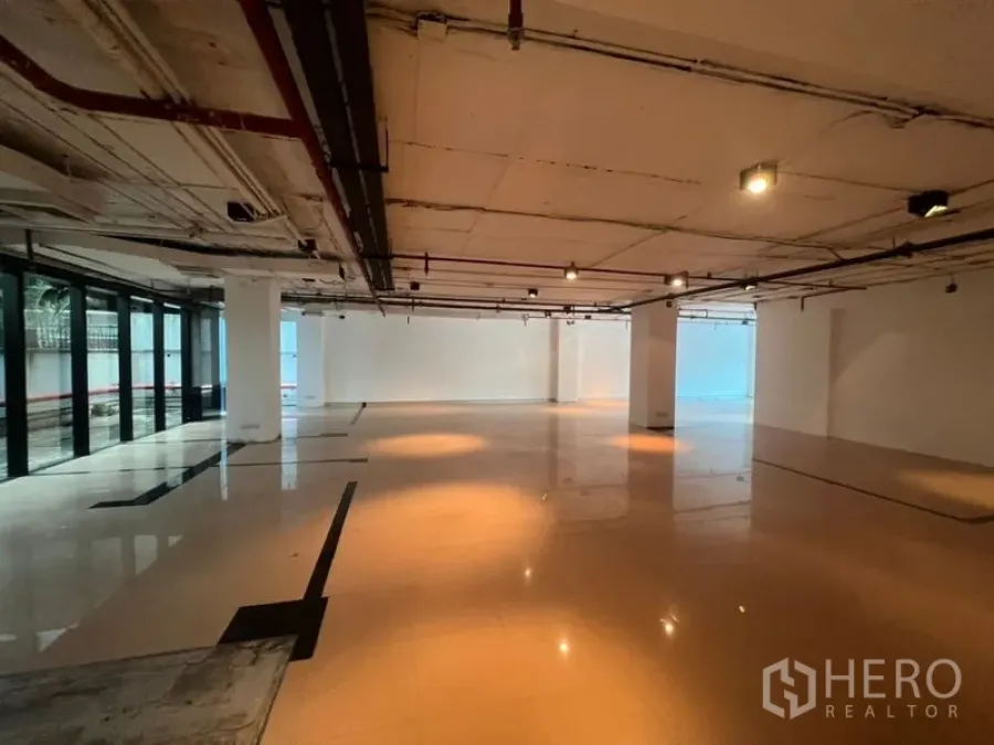 Office Space for rent in Watthana, Bangkok - Spacious open-plan office with polished floors, exposed ceiling services, track lighting and full-height windows.