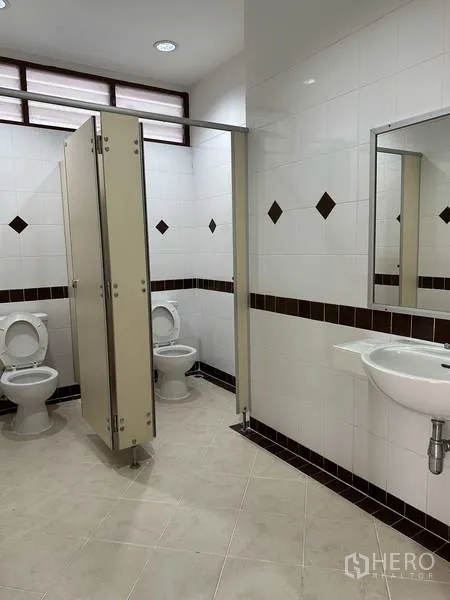 Factory for rent in Bang Phli, Samut Prakan - Clean tiled restrooms with cubicles and basins inside the facility.