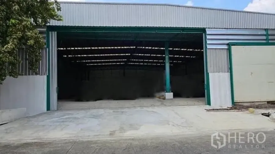 Warehouse for rent in Bang Bon, Bangkok - Wide warehouse entrance with green steel columns, open bay, and concrete loading apron.
