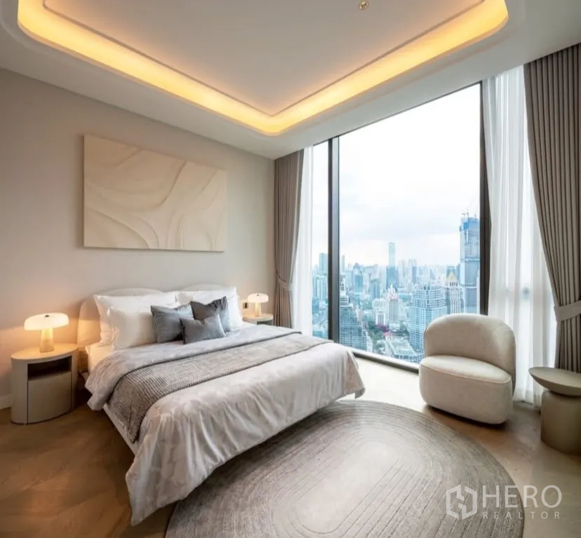 Condominium for rent or sale in Pathum Wan, Bangkok - Bedroom with skyline view through full-height glass and warm cove ceiling lighting.