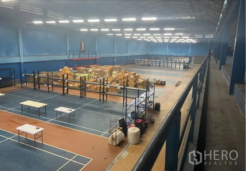 Warehouse for rent in Saphan Sung, Bangkok - Wide indoor storage area with shelving, packages and continuous overhead lights.