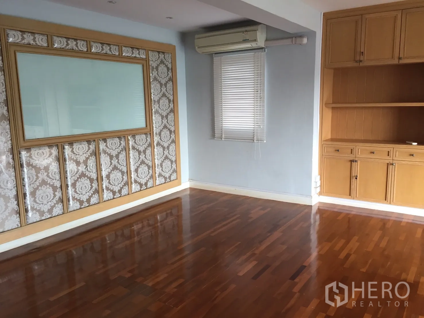Home Office for rent or sale in Suan Luang, Bangkok - Empty room with built-in wooden cabinetry, air conditioner, and decorative wall panel.