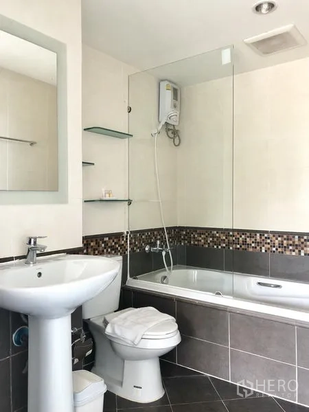 Condominium for rent in Khlong Toei, Bangkok - Modern bathroom with bathtub, glass partition and mosaic tile accent at Waterford Sukhumvit 50.