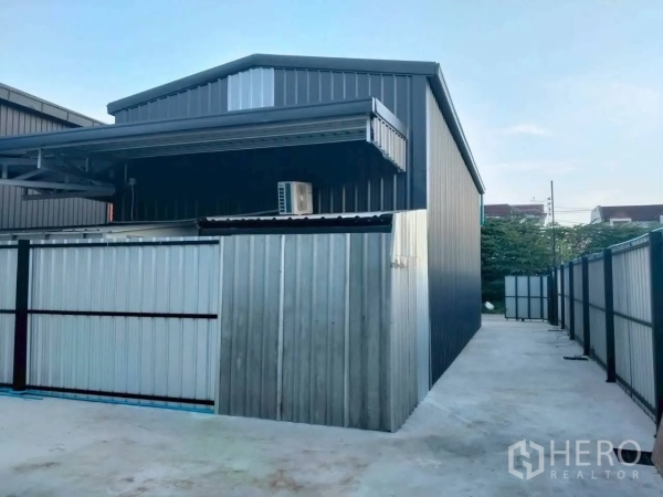 Warehouse for rent in Lat Phrao, Bangkok - Metal-clad warehouse exterior with gated driveway and perimeter fencing.