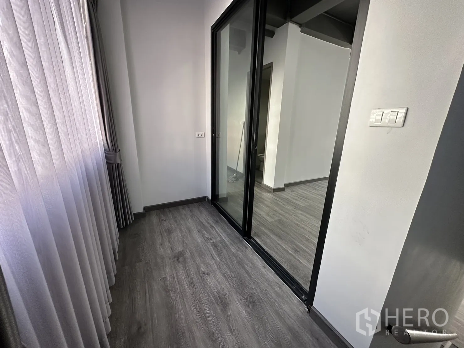 Home Office for rent or sale in Suan Luang, Bangkok - Narrow corridor with sliding glass door and tall curtains leading into a room.