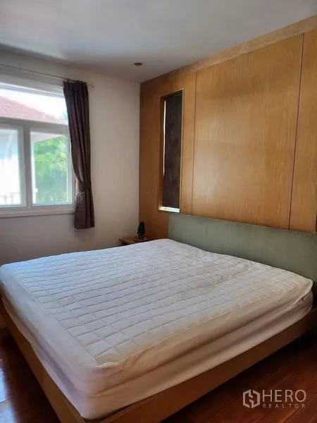 Detached House for rent in Bang Kapi, Bangkok - Cozy bedroom with built-in headboard, wood accents and large window.