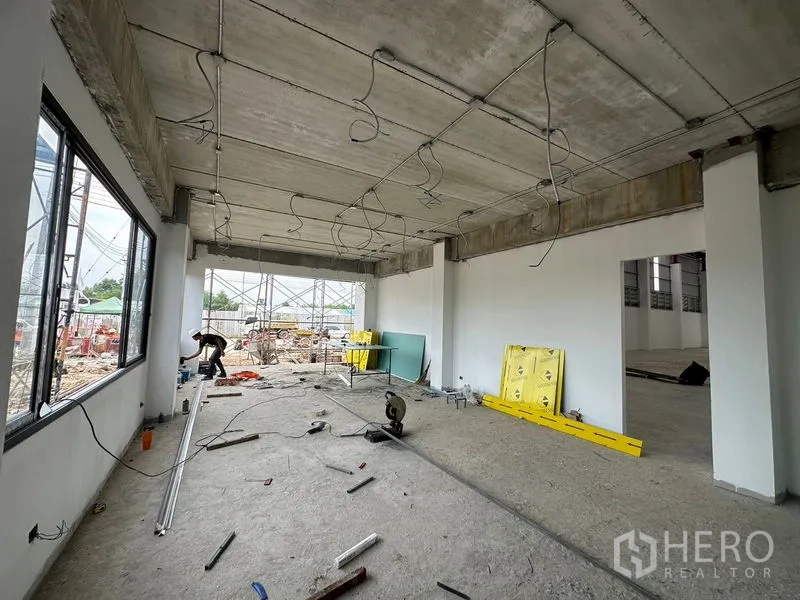 Warehouse for rent or sale in Lam Luk Ka, Pathum Thani - Ground‑floor office area under fit‑out with exposed conduits and large windows.