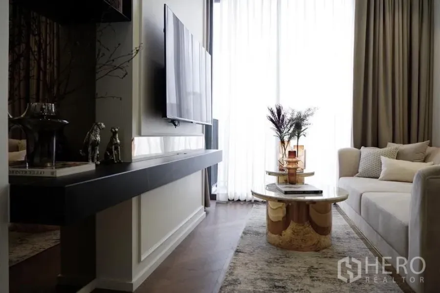 Condominium for rent in Pathum Wan, Bangkok - Elegant living room with wall-mounted TV and round marble coffee table