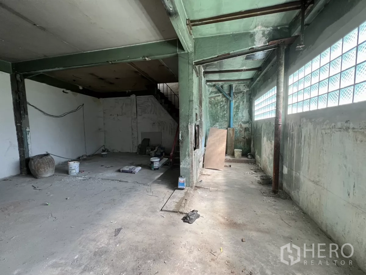 Shophouse for sale in Suan Luang, Bangkok - Long ground-floor area with glass block wall, columns and unfinished surfaces.