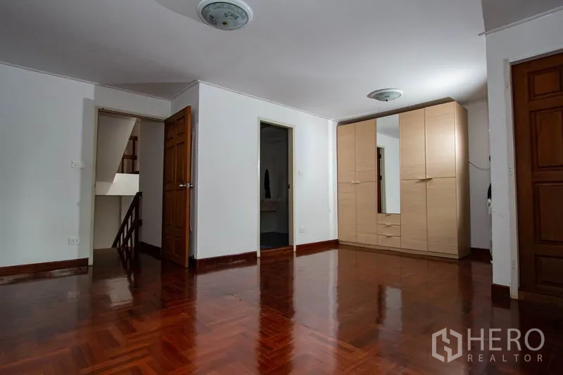 Townhouse for rent in Khlong Toei, Bangkok - Upper floor multipurpose room with wardrobe and glossy wooden floors.