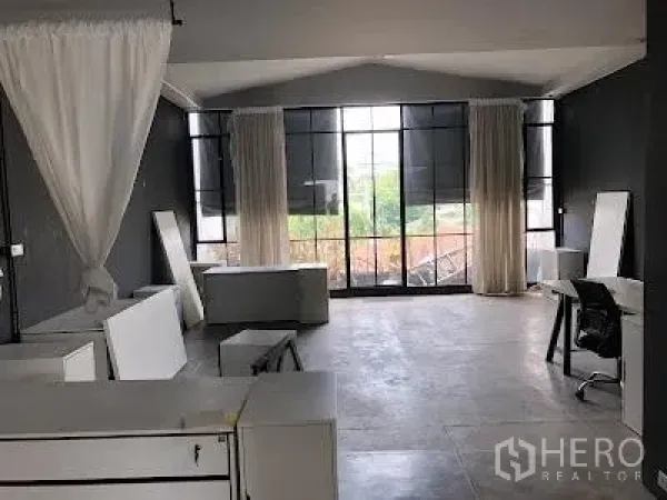 Home Office for rent in Watthana, Bangkok - Bright workspace with large black-framed windows, curtains and scattered desks in an open layout.