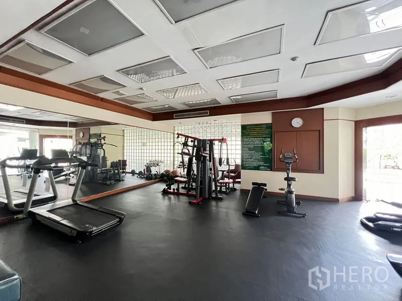 Condominium for rent or sale in Khlong Toei, Bangkok - Condominium fitness center with treadmills, weight machines and wall mirrors.
