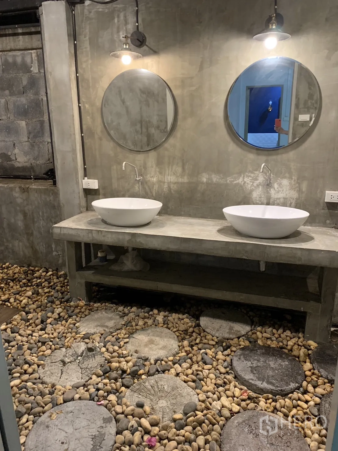 Townhouse for rent in Watthana, Bangkok - Double vanity with round mirrors in a concrete industrial bathroom.