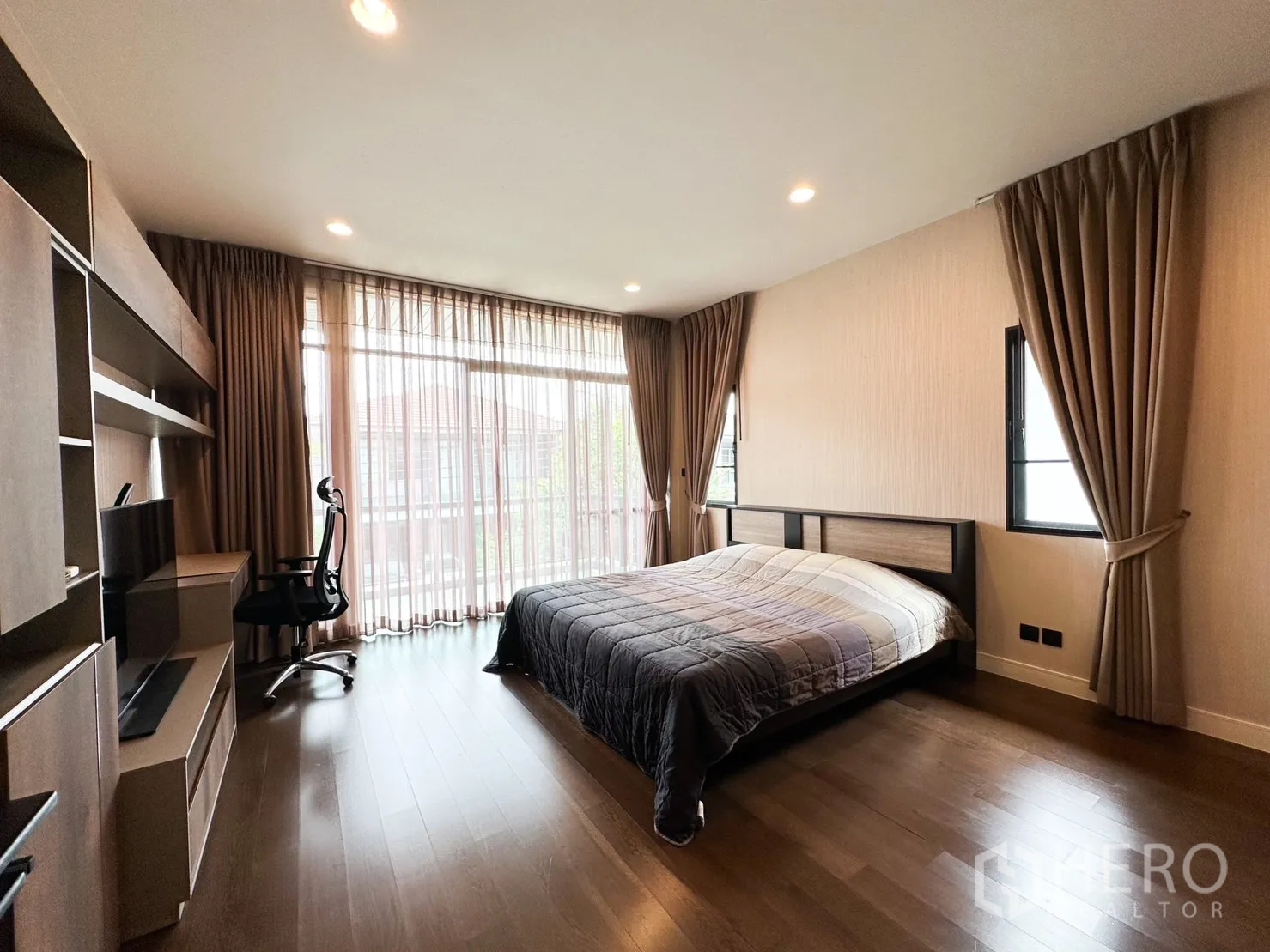 Detached House for rent or sale in Bang Kapi, Bangkok - Spacious master bedroom with wood floors, work desk and floor-to-ceiling curtains.