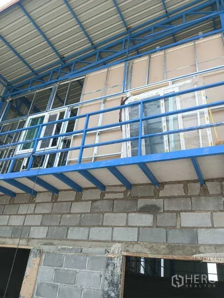 Warehouse for rent in Pathum Thani - Close-up of a blue steel mezzanine with framed windows on an unfinished warehouse facade in Khlong Luang.