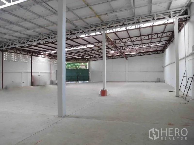 Warehouse for rent in Wang Thonglang, Bangkok - Spacious warehouse bay with concrete floor, metal roof structure and side access door.
