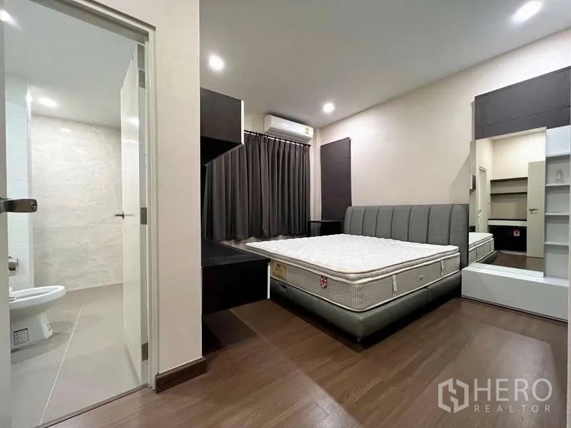 Detached House for sale in Prawet, Bangkok - Guest bedroom with padded bedframe, ensuite access, built-in cabinetry, and dark curtains.