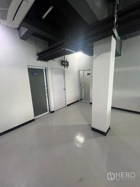 Retail Space for rent in Watthana, Bangkok - Service area with multiple doors for storage or staff rooms beneath exposed ductwork.