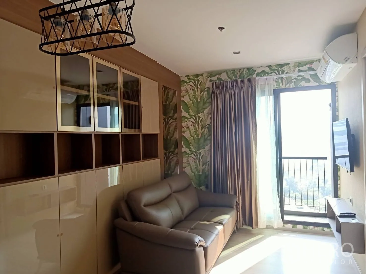 คอนโด for rent in Pathum Wan, Bangkok - ห้องนั่งเล่นสว่างด้วยแสงธรรมชาติ โซฟาหนัง ตู้บิลท์อิน ทีวีติดผนัง และระเบียง