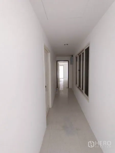 Factory for rent in Lam Luk Ka, Pathum Thani - Bright internal corridor with doors and windows along a tiled passage.