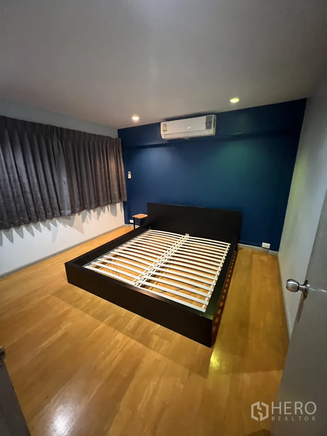 Townhouse for rent in Watthana, Bangkok - Bedroom with platform bed frame, air-conditioner and wood floors.