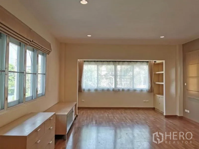 Detached House for rent in Bang Kapi, Bangkok - Large upstairs room with wide windows, built‑in shelving and wood floors filled with natural light.