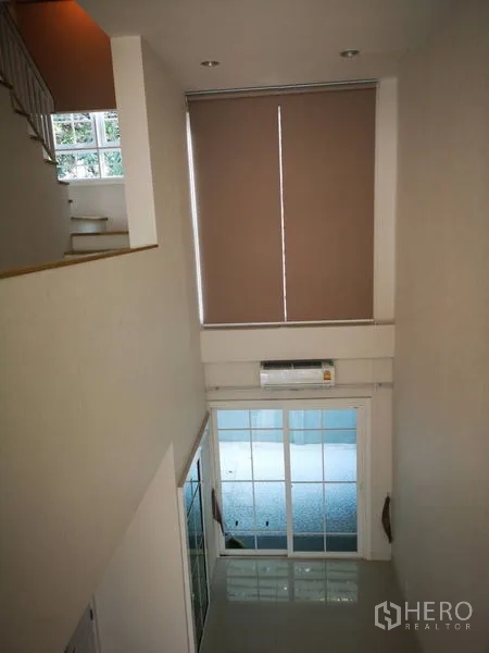 Townhouse for rent in Bang Na, Bangkok - View from mezzanine down to the double-height living space and sliding doors