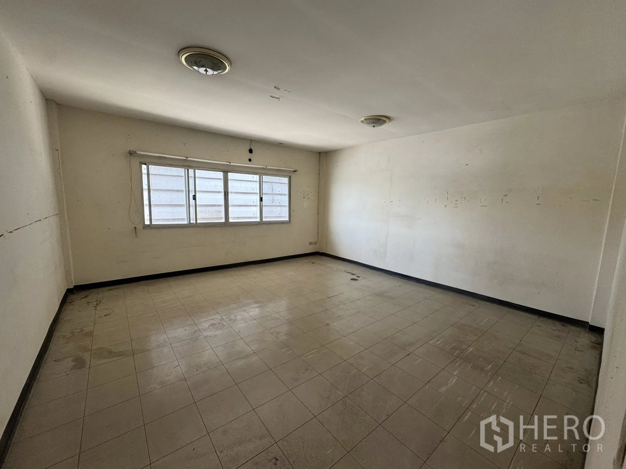 Warehouse for rent in Mueang Samut Sakhon, Samut Sakhon - Vacant room with a long window, beige floor tiles and ceiling lights.