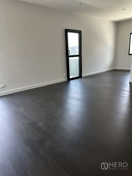 Detached House for sale in Lam Luk Ka, Pathum Thani - Bedroom with balcony door and dark flooring.