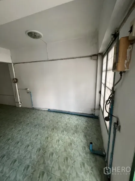 联排别墅 出售在Watthana, Bangkok - 功能角落带明管与绿色地砖，适合作为未来厨房区。