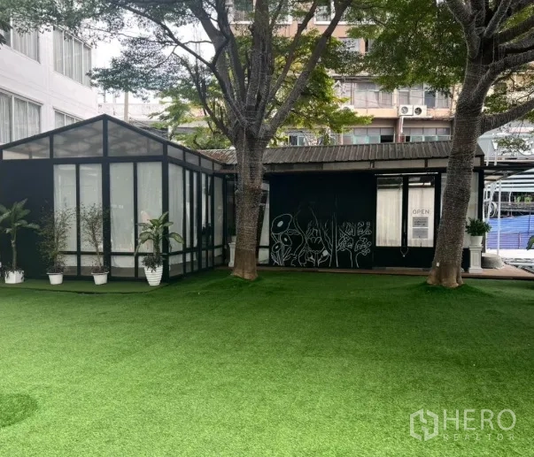 Retail Space for rent in Watthana, Bangkok - Wide lawn frontage with two large trees and connected glass pavilions of the retail space.