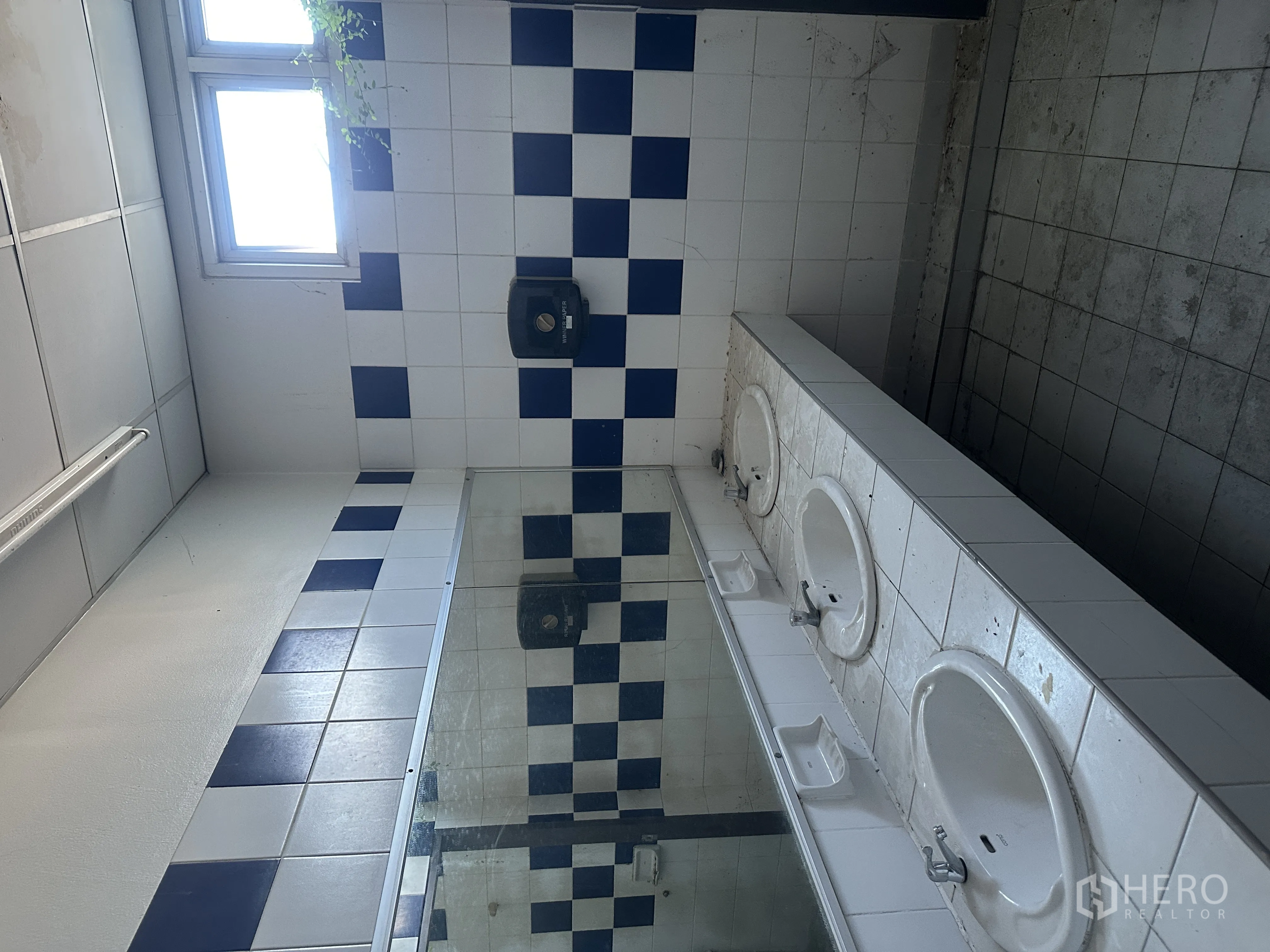 Factory for rent in Bang Pa-in, Phra Nakhon Si Ayutthaya - Restroom with blue and white tiled walls, long mirror, and multiple sinks beneath a window.