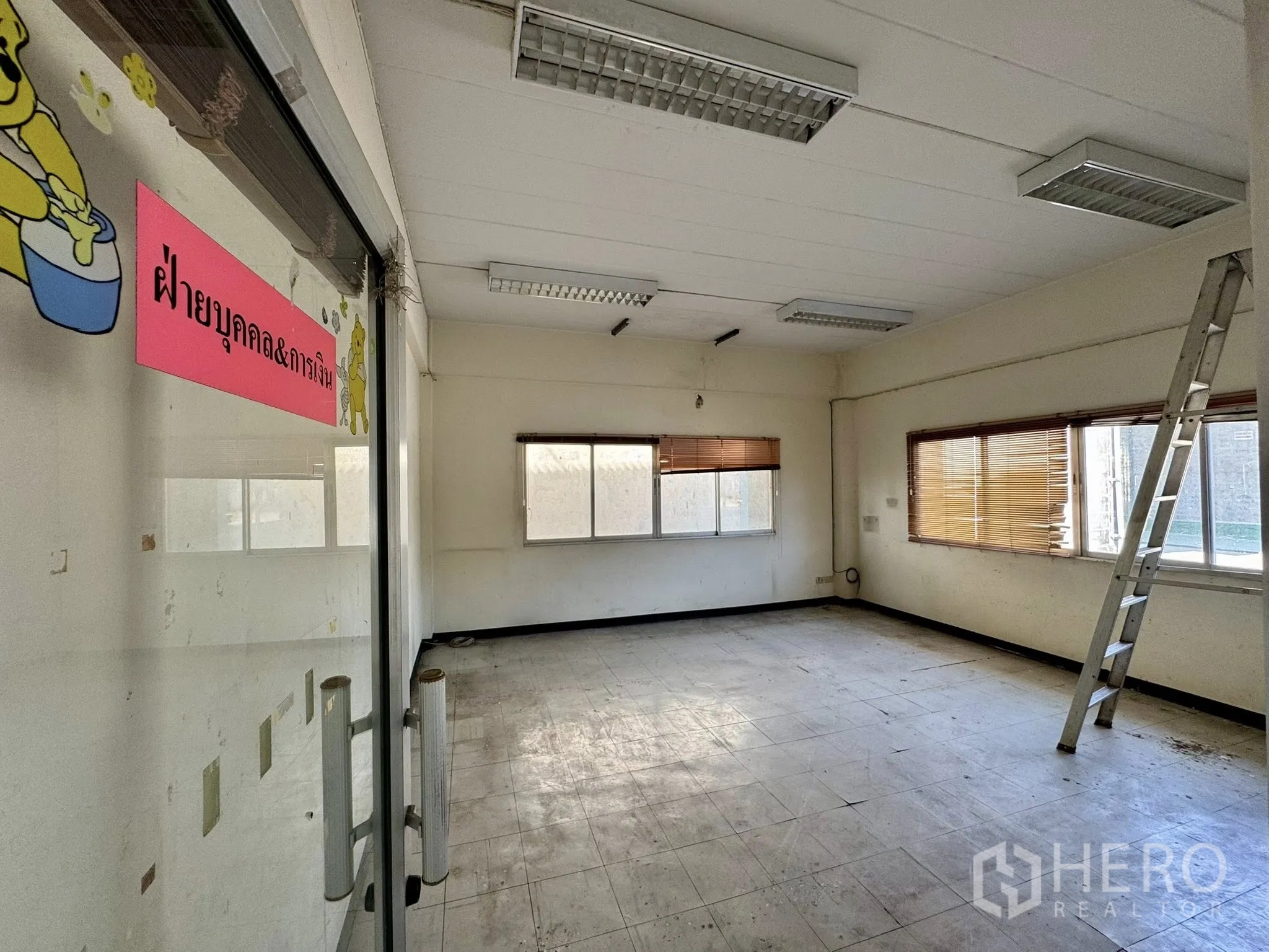 Warehouse for rent in Mueang Samut Sakhon, Samut Sakhon - Corner office behind a glass door with a Thai sign and a ladder by the window.