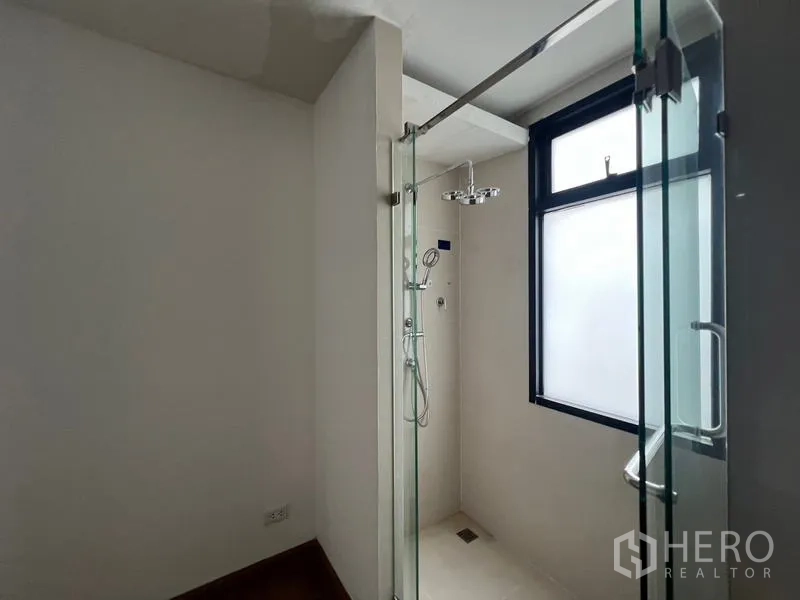 Townhouse for rent or sale in Khlong Toei, Bangkok - Bright bathroom with a frosted window and glass-enclosed rain shower.