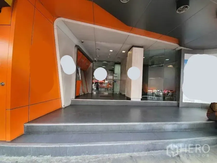 Shophouse for rent in Bang Rak, Bangkok - Modern shophouse entrance with orange cladding, steps and a glass storefront.