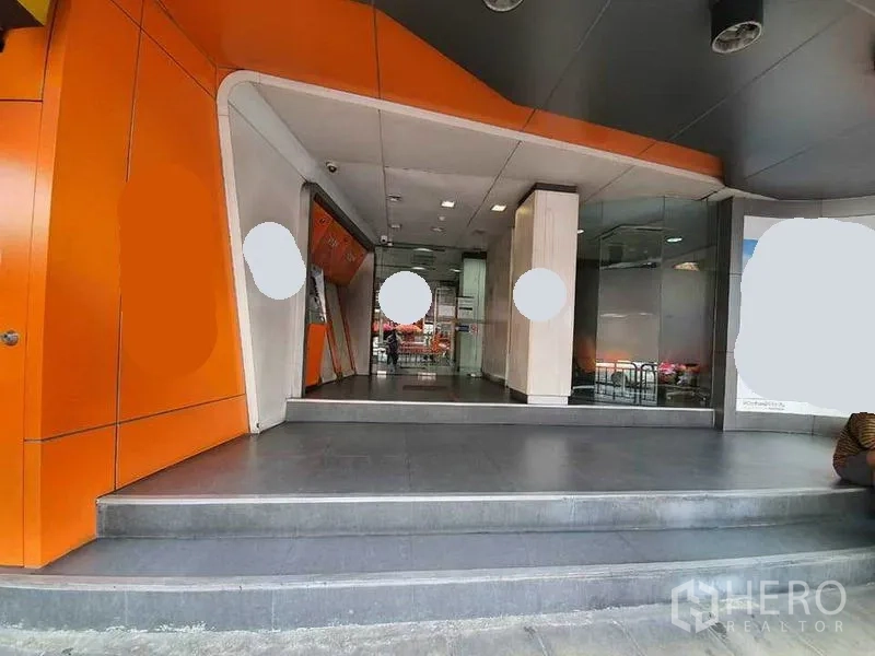 Shophouse for rent in Bang Rak, Bangkok - Modern shophouse entrance with orange cladding, steps and a glass storefront.