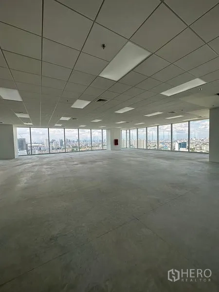 Office Space for rent in Bang Na, Bangkok - Open-plan office floor in Bang Na with drop ceiling, lighting, and full-height windows showcasing a wide Bangkok skyline view.