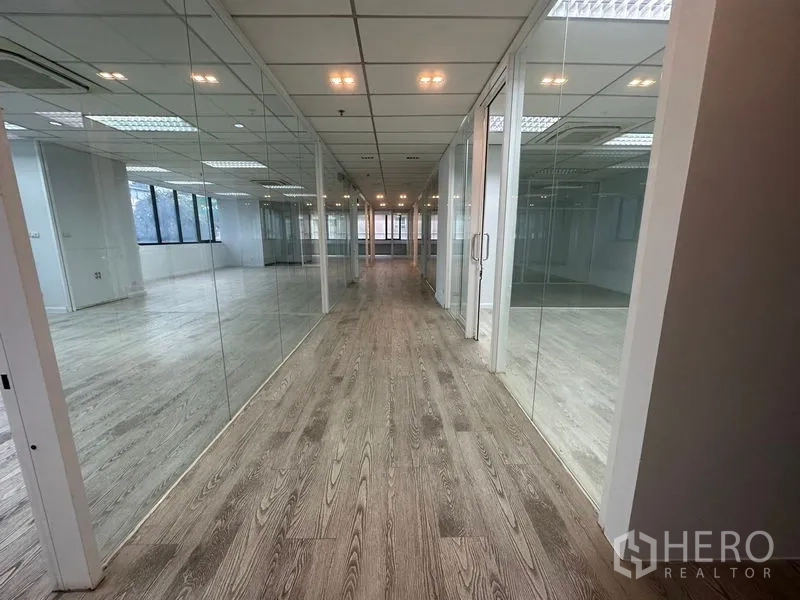 Office Space for rent in Din Daeng, Bangkok - Hallway of glass meeting rooms illuminated by recessed lights.
