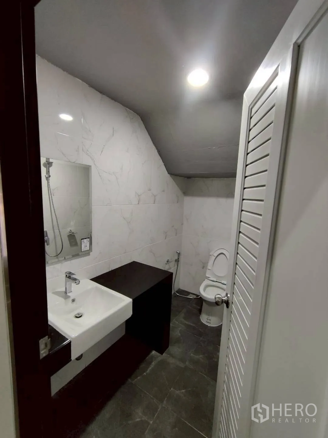 Factory for rent in Krathum Baen, Samut Sakhon - Modern restroom with tiled walls, sink, mirror, and toilet.